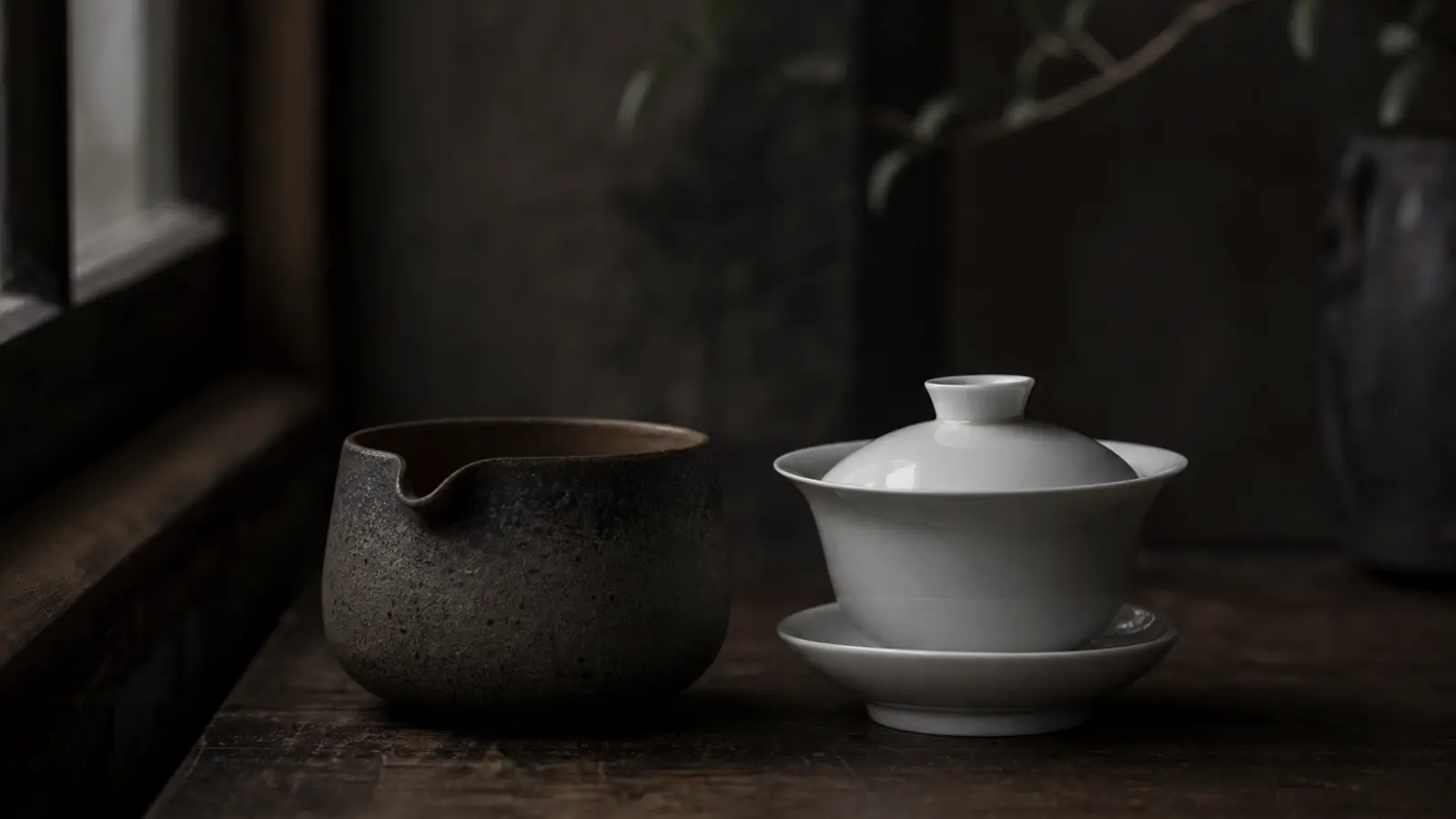 Japanese houhin and Chinese white porcelain gaiwan side by side on wood surface, comparing two traditional lidless tea brewing vessels.