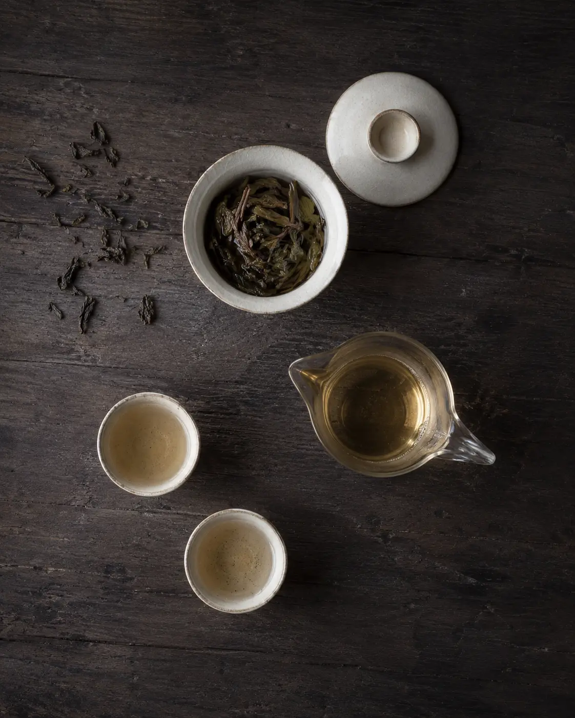 White porcelain gaiwan and tea cups on a wooden tea tray