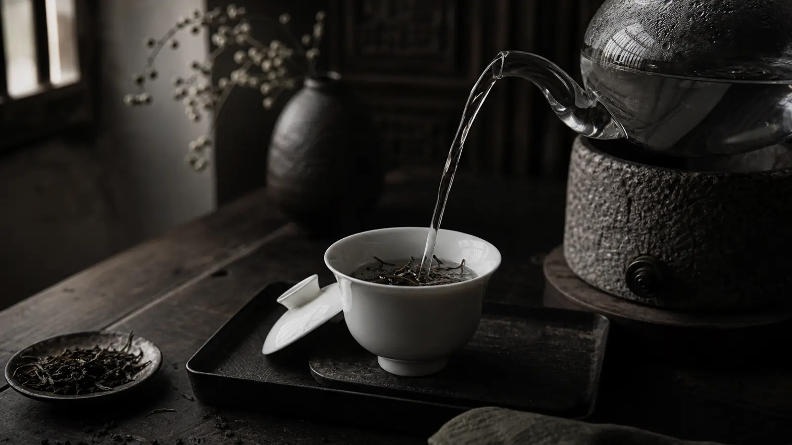 Crystal-clear water pouring from a glass kettle over tea leaves in a white gaiwan, highlighting water purity in natural light.